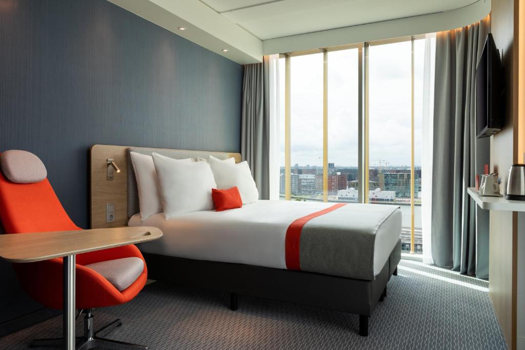 a hotel room with a bed and a desk and a window at Holiday Inn Express Amsterdam - North Riverside by IHG in Amsterdam