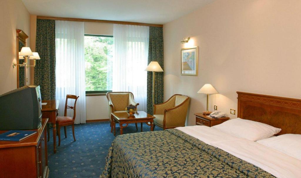 pokój hotelowy z łóżkiem, krzesłami i oknem w obiekcie Hotel AS w Zagrzebiu