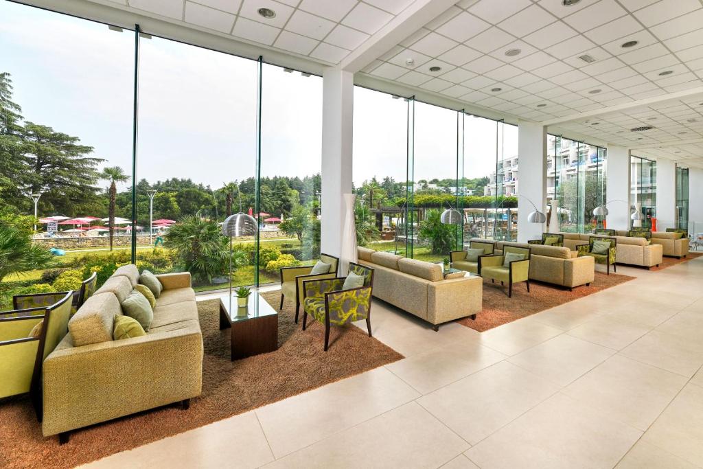 a lobby with couches and tables and large windows at Hotel Mediteran Plava Laguna in Poreč