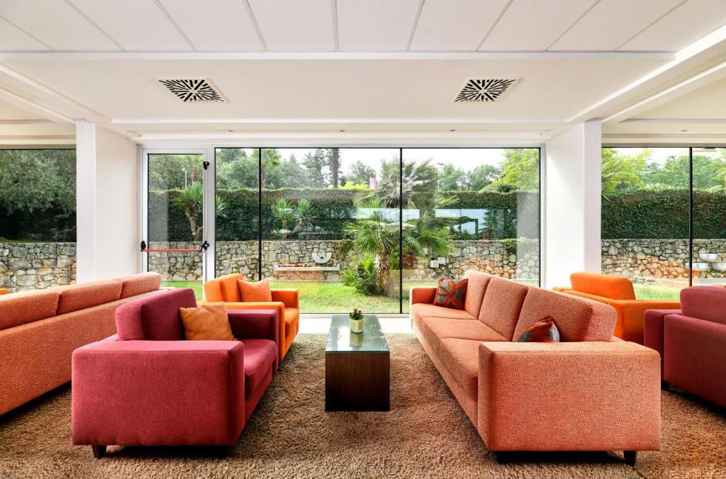 a living room with orange furniture and large windows at Hotel Mediteran Plava Laguna in Poreč