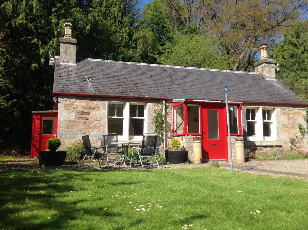 a red and white cottage with a table and chairs at Annslea Garden Cottage in Pitlochry