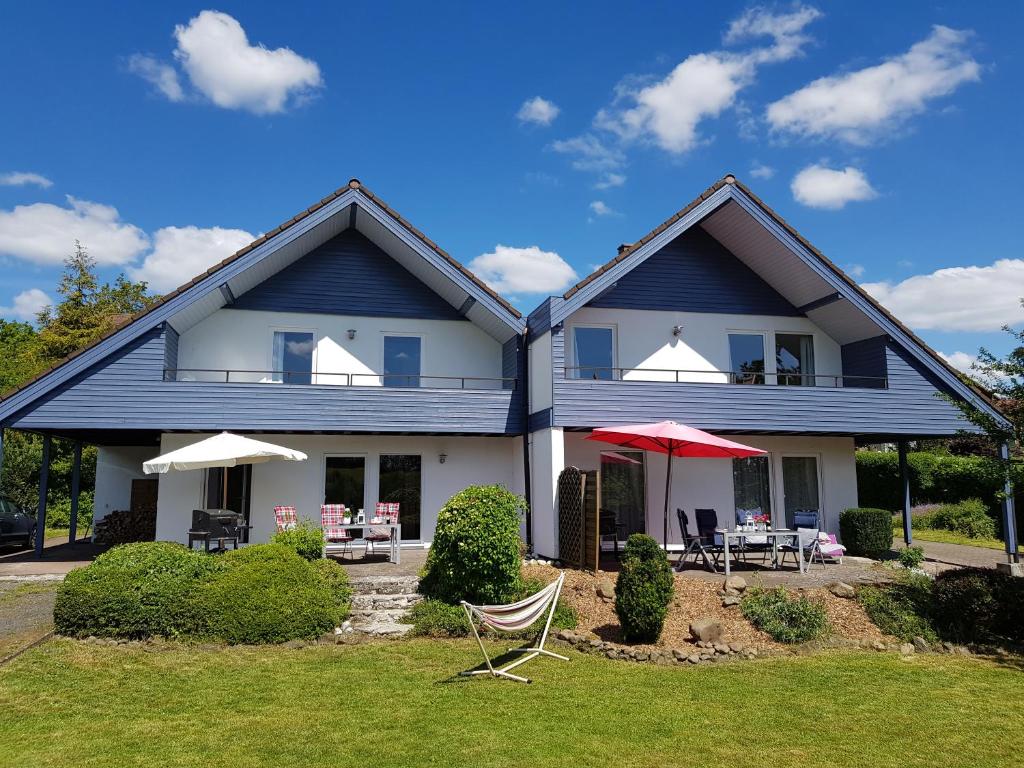 een huis met stoelen en parasols in de tuin bij Ferienhäuser Rhön - Haus Natalie & Haus Helene in Hausen