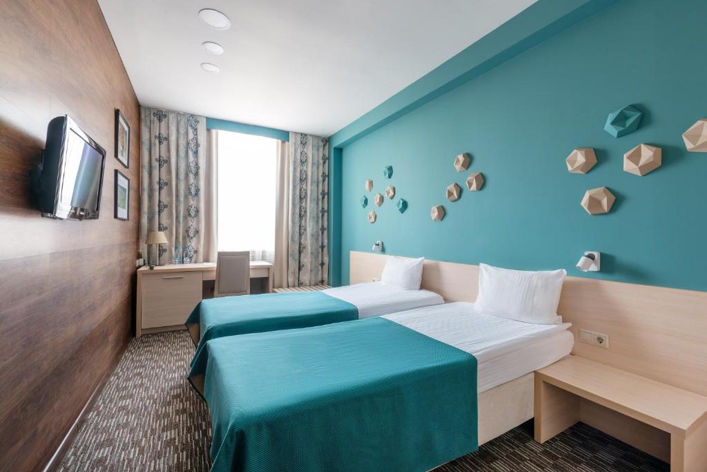two beds in a hotel room with blue walls at Business Hotel Diplomat in Nizhny Novgorod