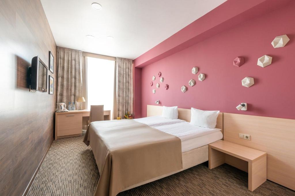 a hotel room with a bed and a pink wall at Business Hotel Diplomat in Nizhny Novgorod