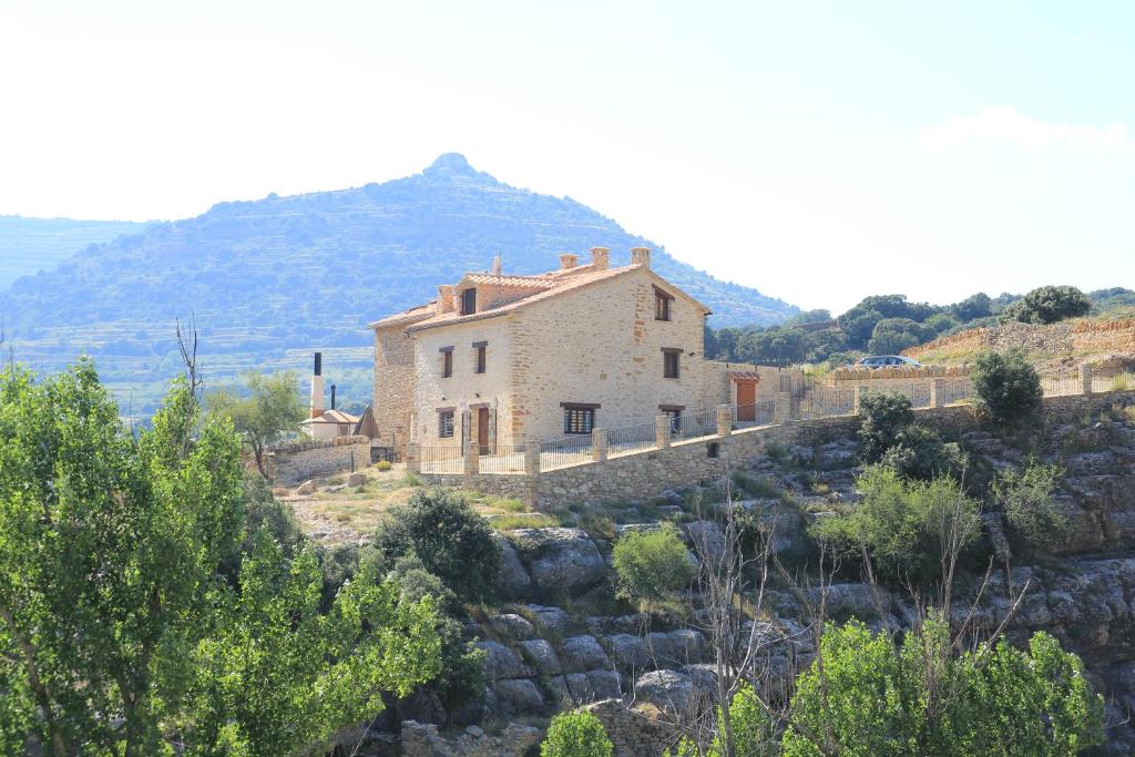 ein Haus auf einem Hügel mit einem Berg im Hintergrund in der Unterkunft MOLINO DOLZ in La Iglesuela del Cid