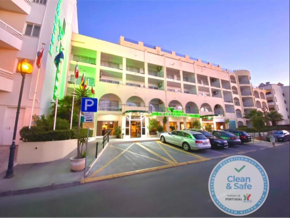 a building with cars parked in front of a parking lot at Aparthotel Calema Avenida Jardim in Monte Gordo