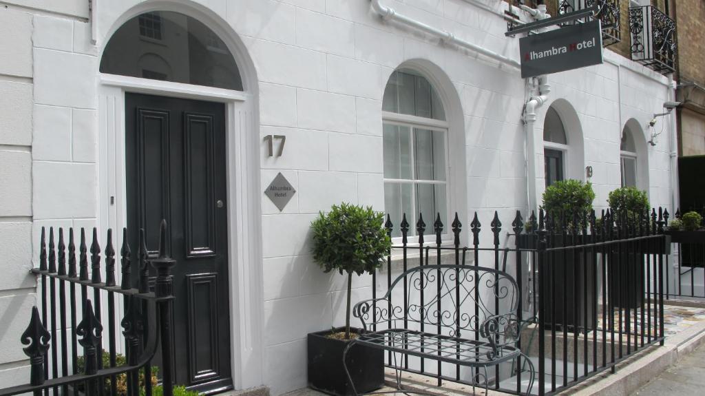a black door on a white building with a bench at Alhambra Hotel in London