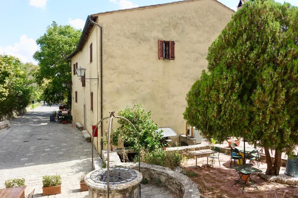 a building with a tree next to a street at Casa alla Vecchia Posta di Bagno Vignoni in Bagno Vignoni