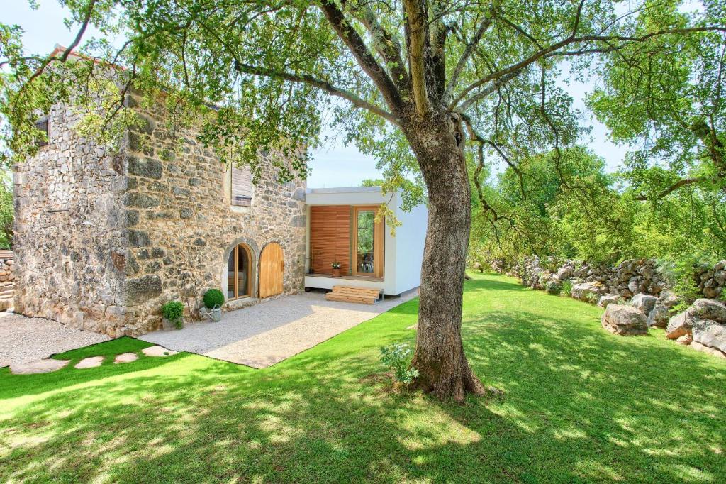 a stone house with a tree in the yard at Vila Anka in Malinska
