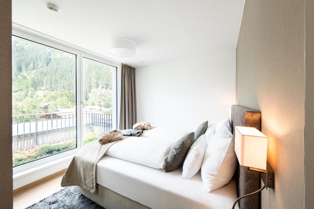 a bedroom with a bed and a large window at MANNI village - lifestyle apartments in Mayrhofen