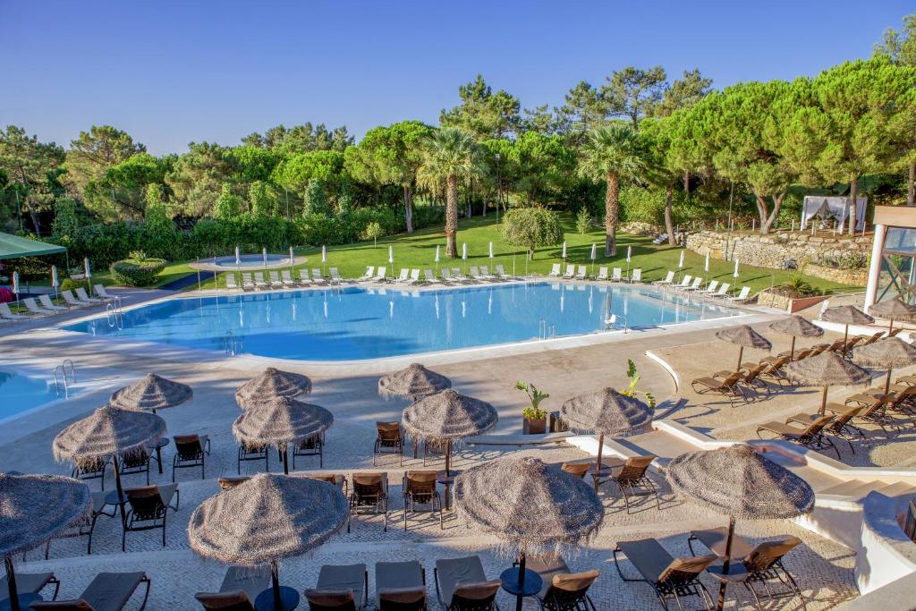 una gran piscina con sombrillas, mesas y sillas en Vilar do Golf, en Quinta do Lago