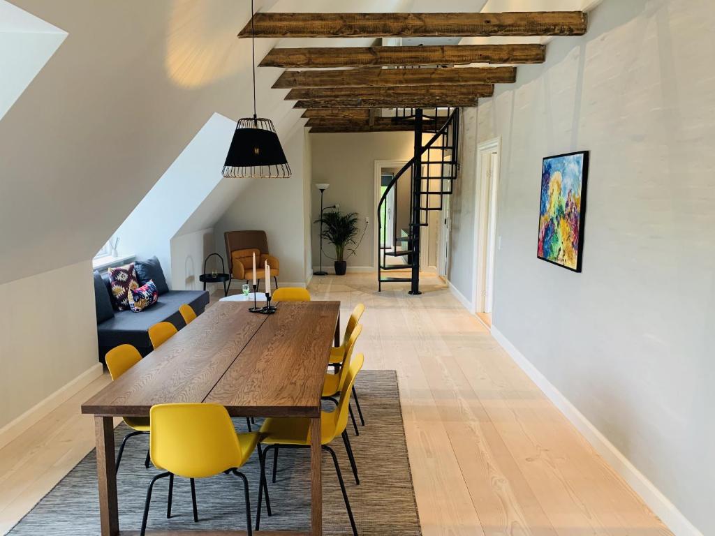 a dining room with a wooden table and yellow chairs at aday - 3 bedroom - Modern Living Apartment - Aalborg Center in Aalborg