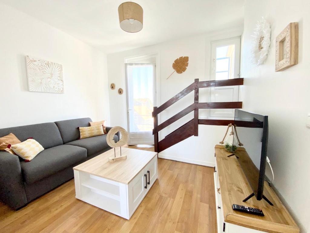 ein Wohnzimmer mit einem Sofa und einer Wendeltreppe in der Unterkunft Le Wood, entre centre ville et plage in Mers-les-Bains