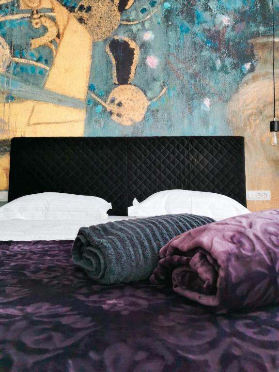 a bedroom with a bed with purple sheets and a painting at Litore in Pula