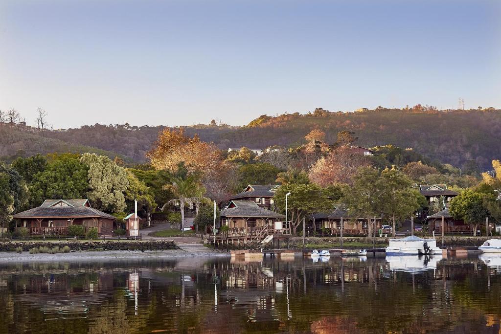 a group of houses on a lake with boats in the water at First Group Knysna River Club in Knysna