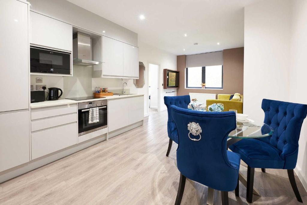 a kitchen and living room with blue chairs and a table at Luxustay Clyde House in Milton Keynes