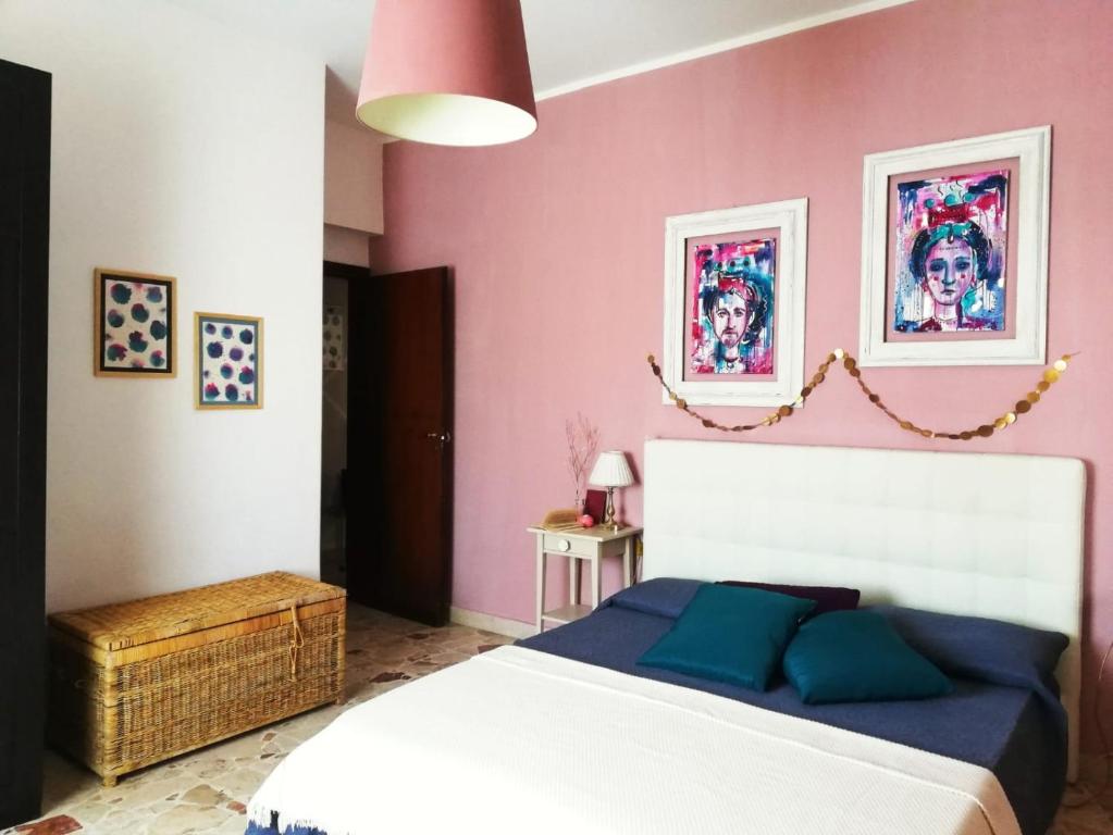 una camera con un letto bianco e una parete rosa di Trinaco B&B a Catania
