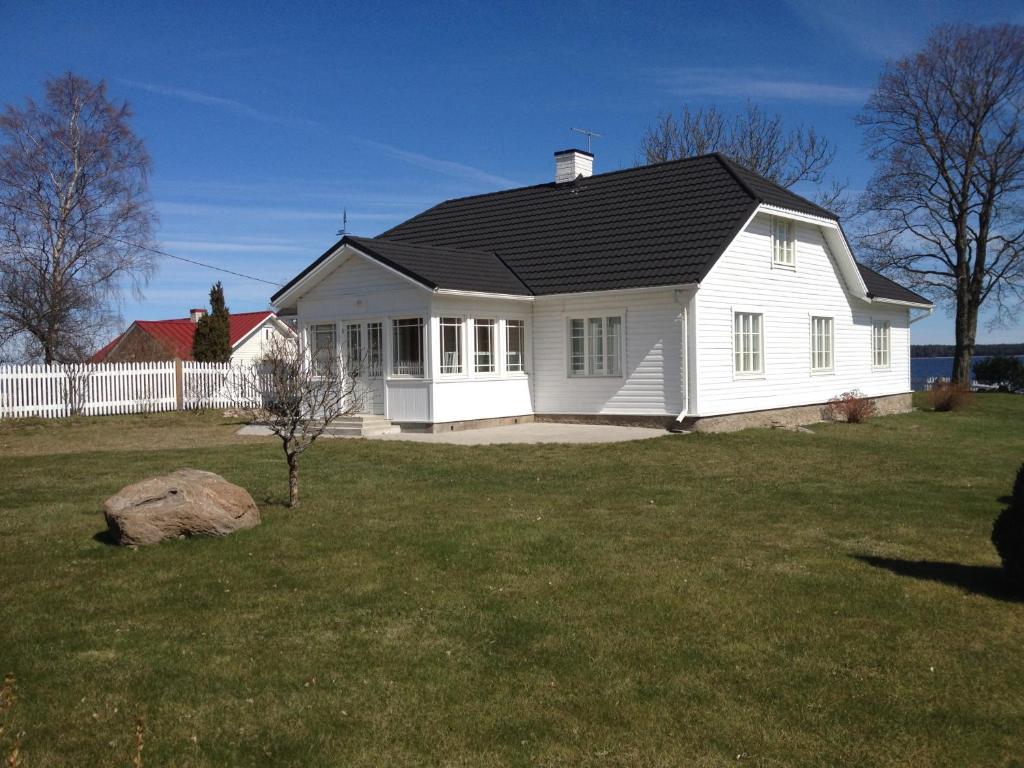 a white house with a black roof on a yard at ÄSSA BEACH HOUSE in Käsmu