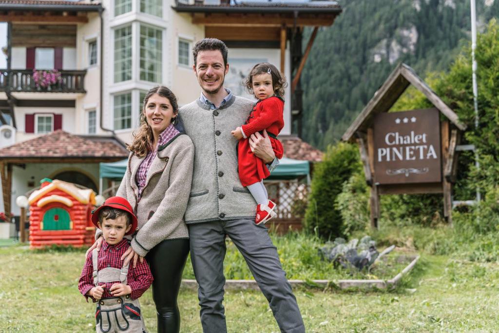 a man and a woman and a child in front of a house at Chalet Pineta relax location in Canazei