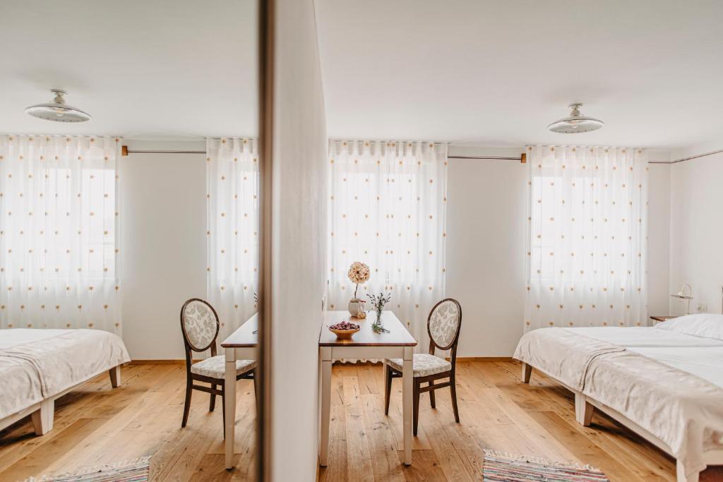 a bedroom with two beds and a table and chairs at Casa Krasna Gourmet Boutique Hotel in Lokev