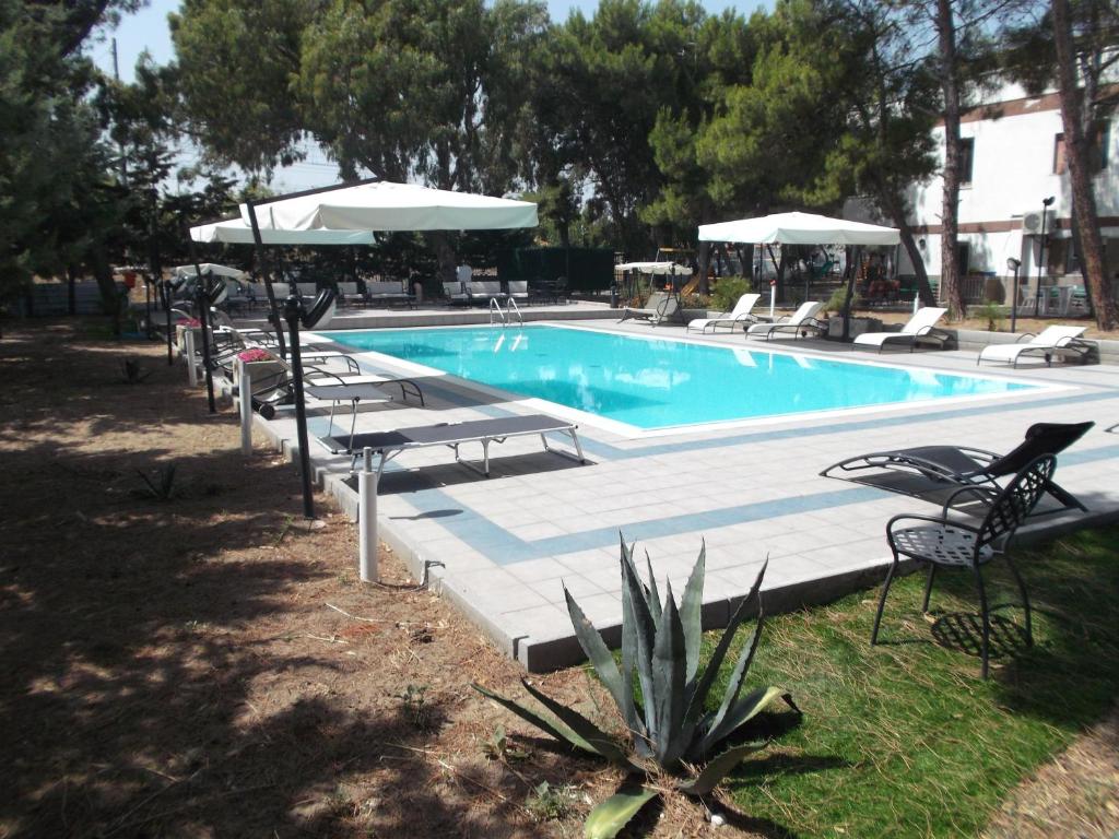 a swimming pool with lounge chairs and umbrellas at Residence MILANO in Chieuti