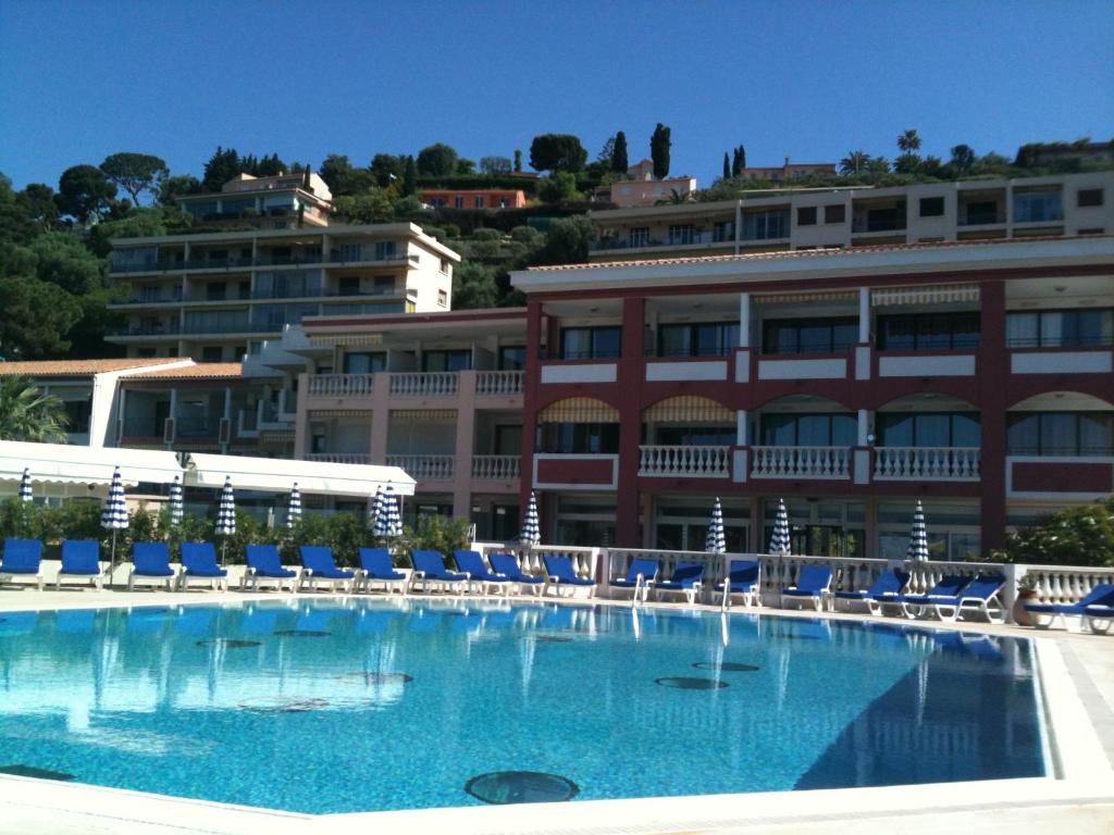 a large swimming pool with blue chairs and a building at Appartement Ange Gardien Vue Mer in Villefranche-sur-Mer