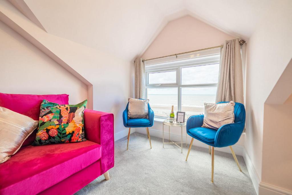 a living room with a pink couch and two blue chairs at Charles Alexander Short Stay - Highcliffe Apartments in Cleveleys