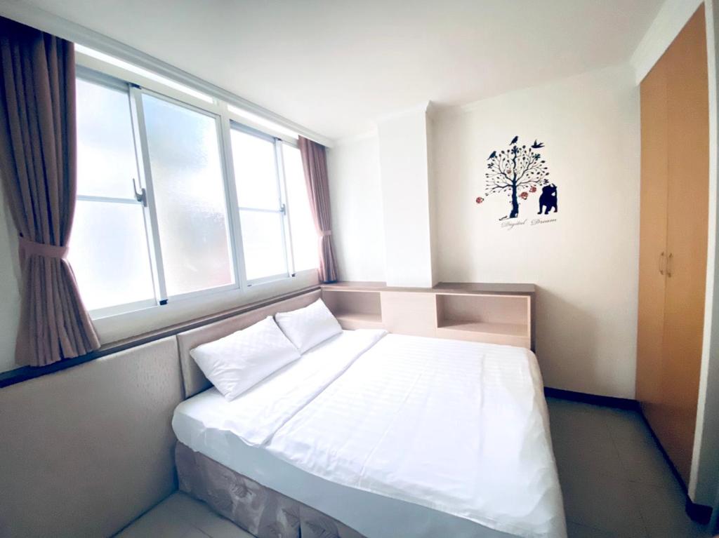 台南的住宿－來七桃旅店，卧室配有一张床铺,墙上挂着一棵树