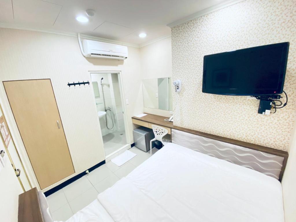 a room with a bed and a tv on the wall at Lai Chi Te Hotel in Tainan