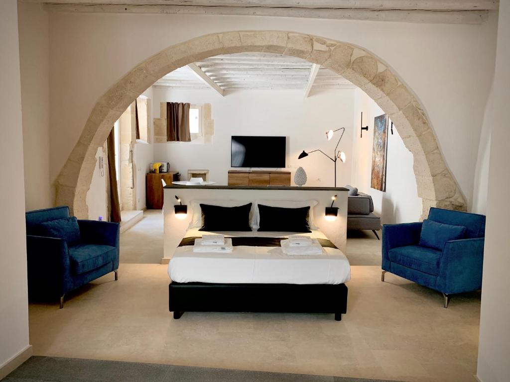 a bedroom with a bed and two blue chairs at Isabella di Castiglia Apartments in Siracusa