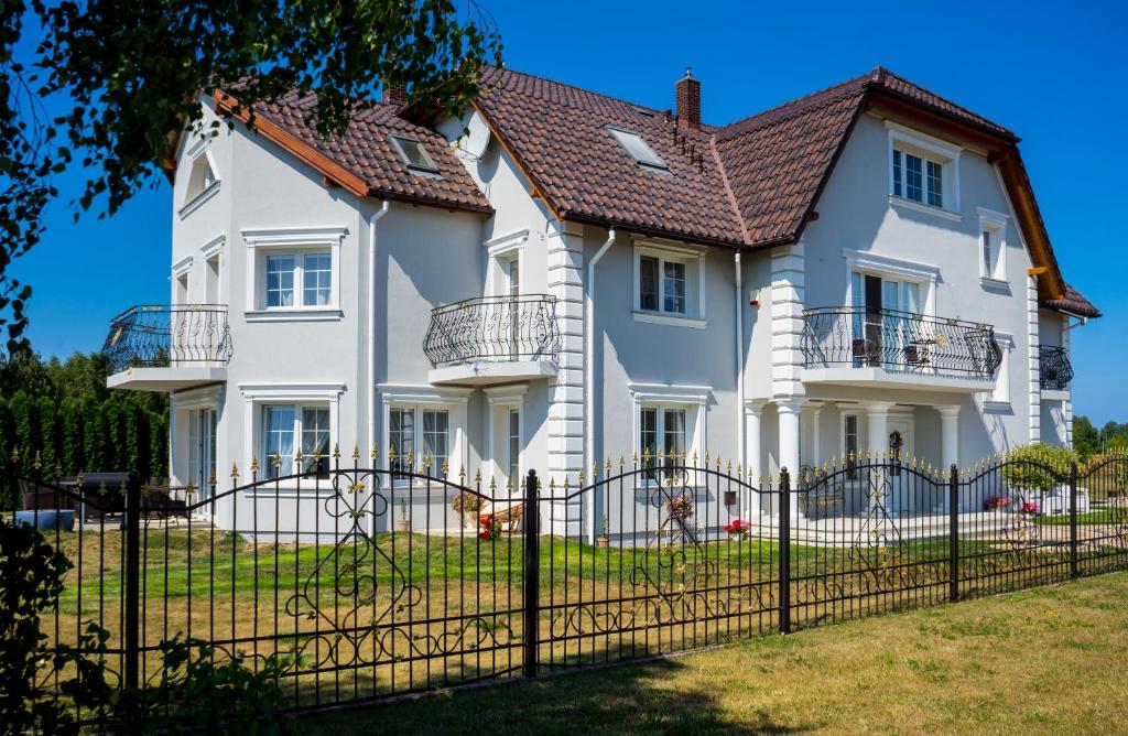 una grande casa bianca con una recinzione nera di WILLA RÓŻA WIATRÓW a Dziwnówek
