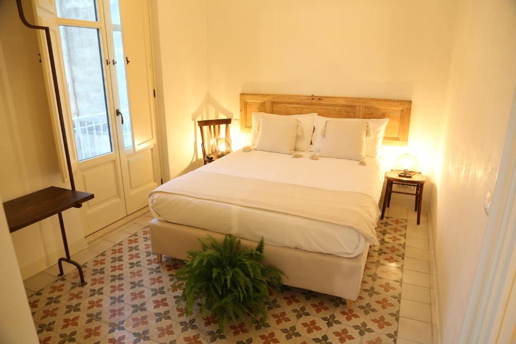una camera da letto con un grande letto bianco e una finestra di DimorAruci - Ospitalità Siciliana a Modica