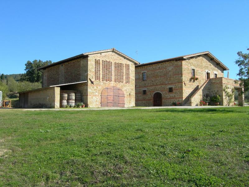 ein großes Backsteingebäude mit einem großen Grasfeld in der Unterkunft Agriturismo Barbi in Monticchiello