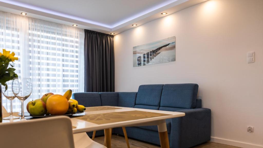ein Wohnzimmer mit einem blauen Sofa und einem Tisch in der Unterkunft Apartament na Rybackiej in Kołobrzeg