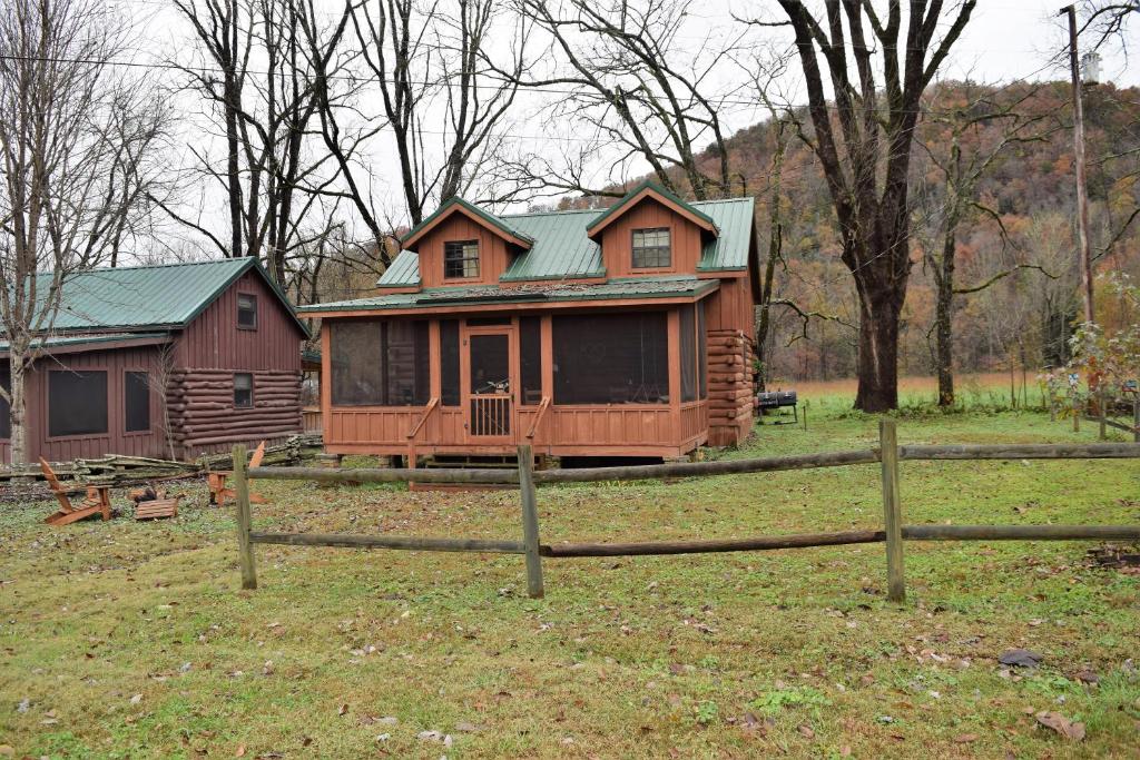 a wooden house with a green roof in a field at River Dreaming in Townsend