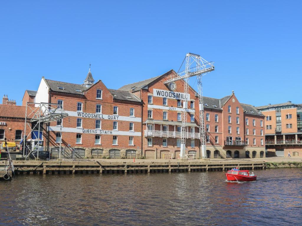 a red boat in the water in front of a building at 12 Woodsmill Quay in York