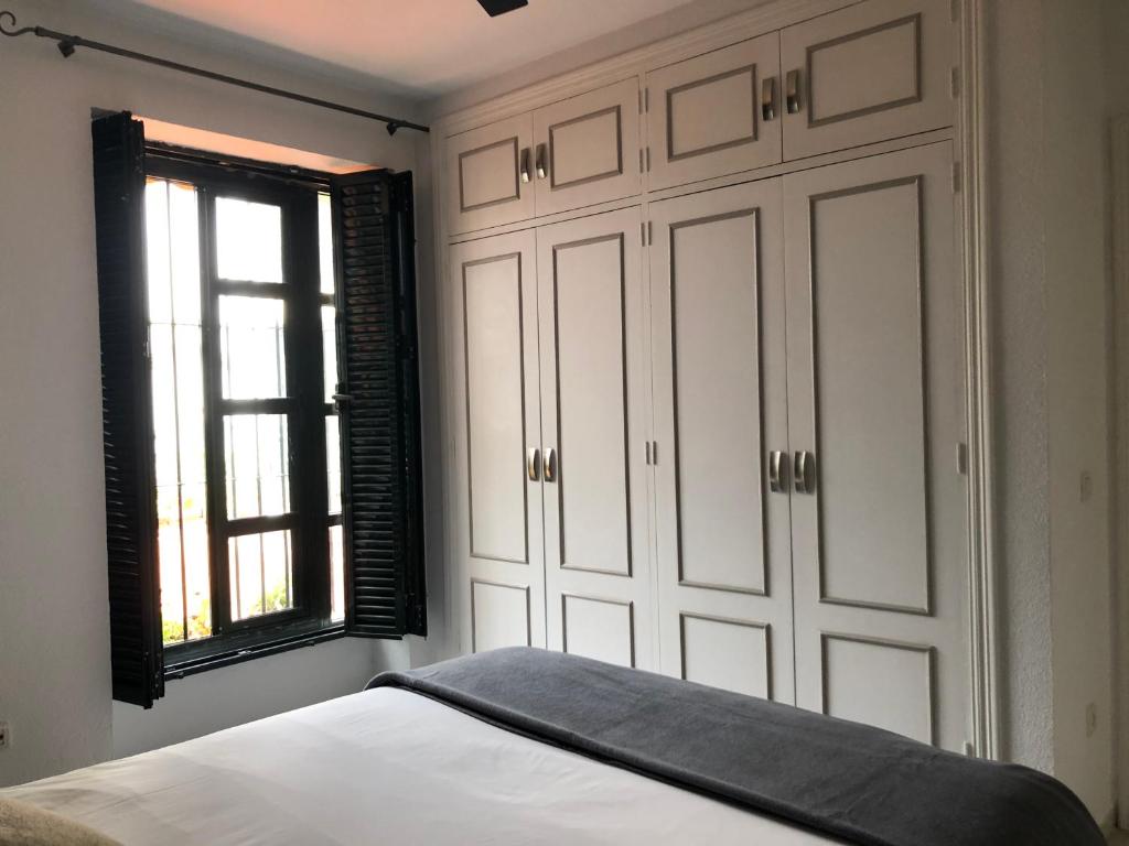 a bedroom with a bed with white cabinets and a window at Apartamento Los Olivos Jerez in Jerez de la Frontera