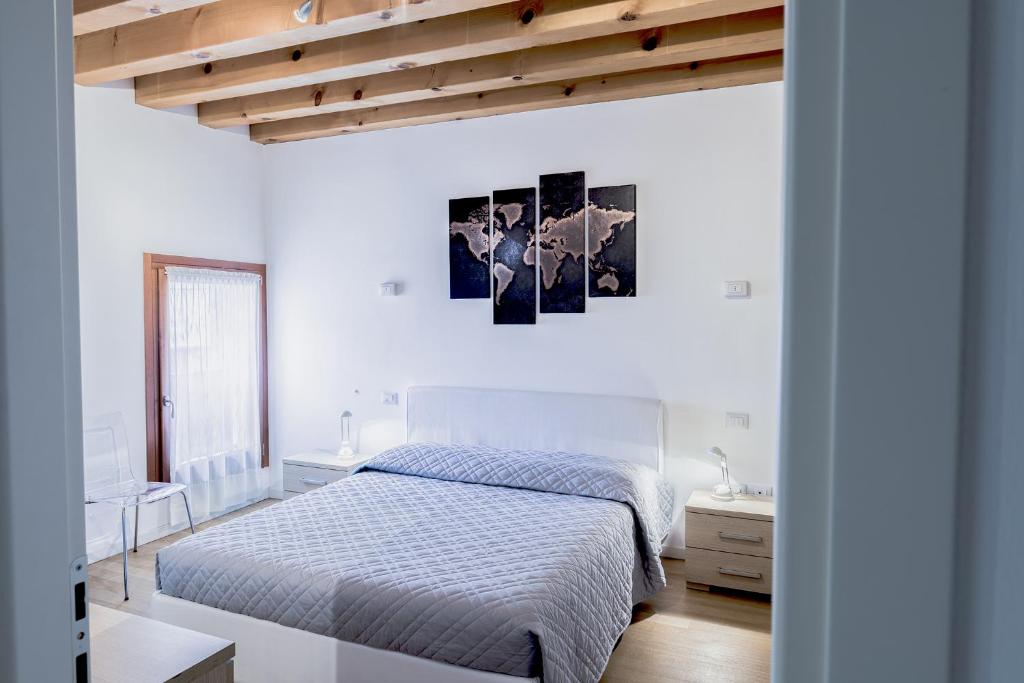 ein weißes Schlafzimmer mit einem Bett und einer Holzdecke in der Unterkunft Vicolo J. Da Ponte - Bassano Centro Storico in Bassano del Grappa