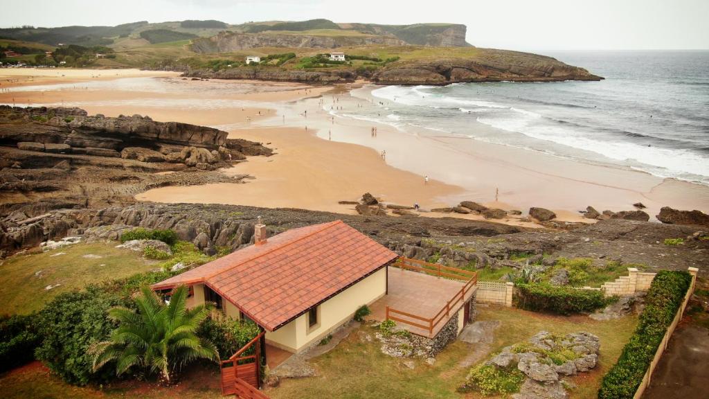 a house on a beach next to the ocean at La Cabaña de la playa in Ajo