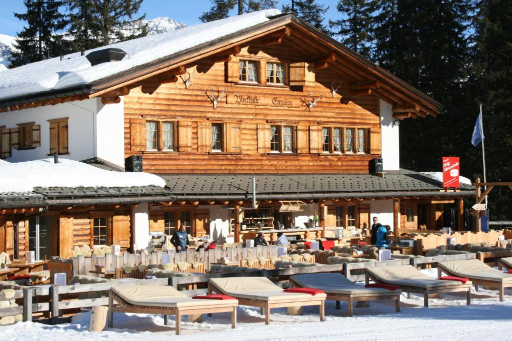 a log building with tables and chairs in the snow at Erezsässhütte in Klosters