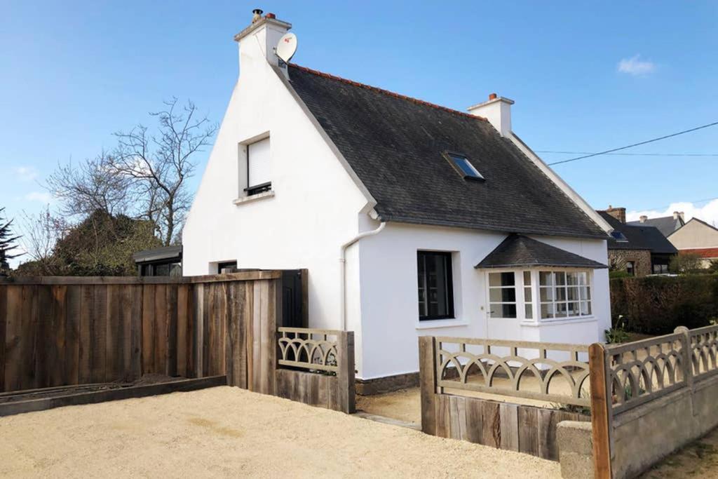 una casa bianca con una recinzione in legno di Maison avec SPA côte de granit rose a Trégastel