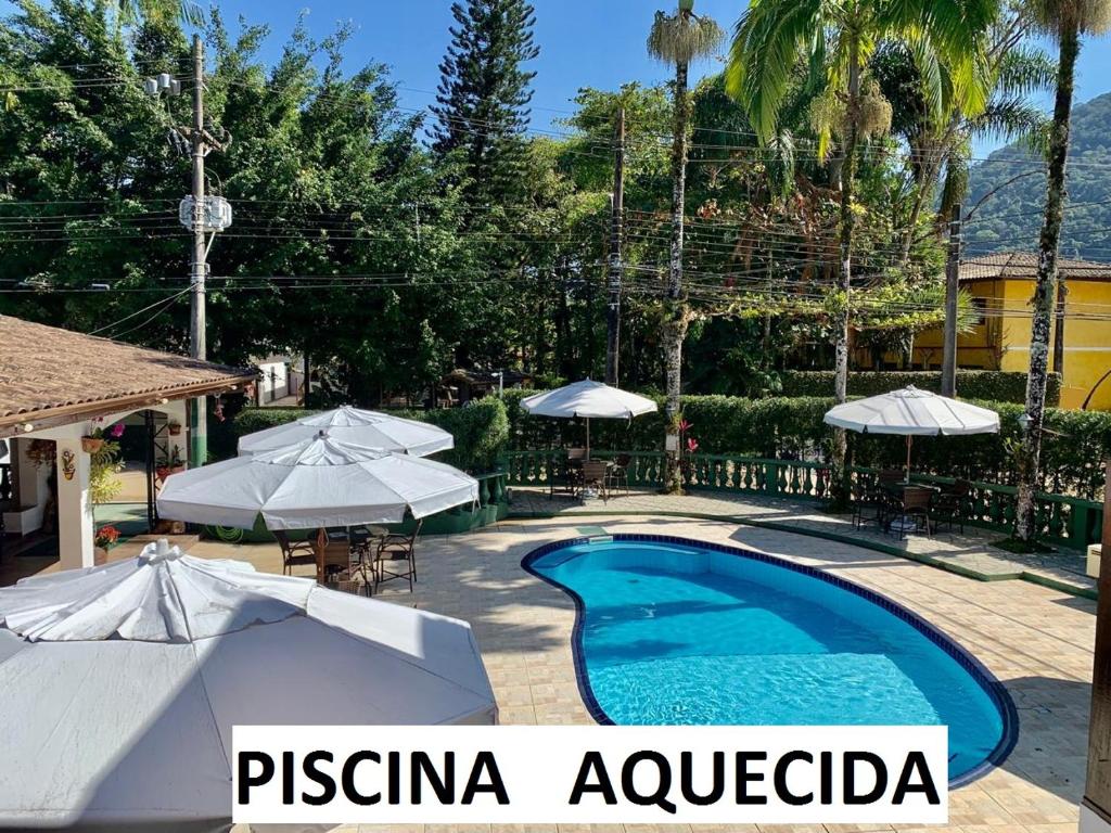 a swimming pool with umbrellas and a resort at Pousada Flores do Lázaro in Ubatuba