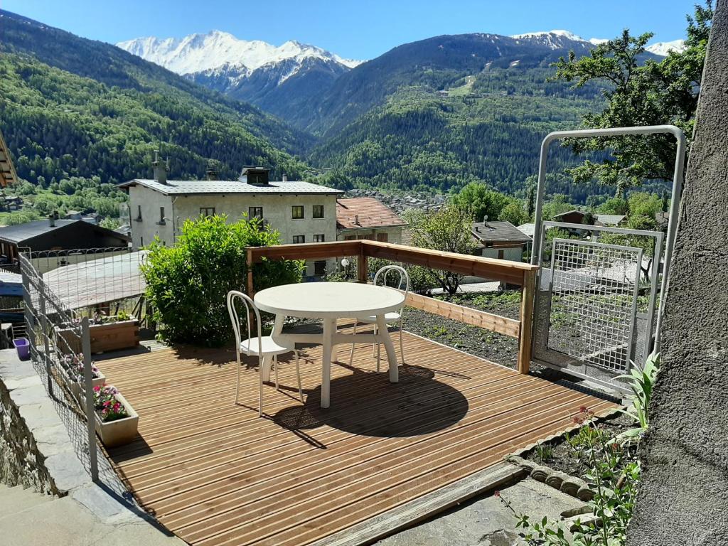 a table and chairs on a wooden deck with mountains at La Maison Trésallet in La Plagne Tarentaise