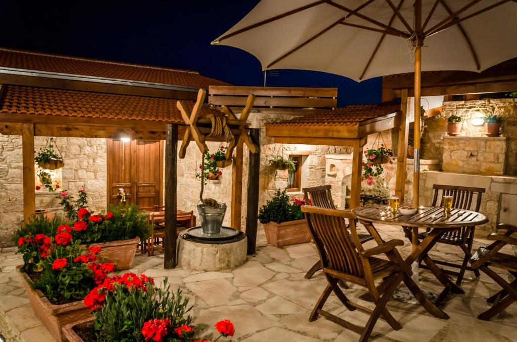 een patio met een tafel met een parasol en bloemen bij Xenios Cottages in Lofou