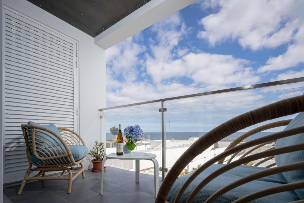 d'un balcon avec des chaises et une table offrant une vue sur la plage. dans l'établissement The Wish São Roque, à Ponta Delgada