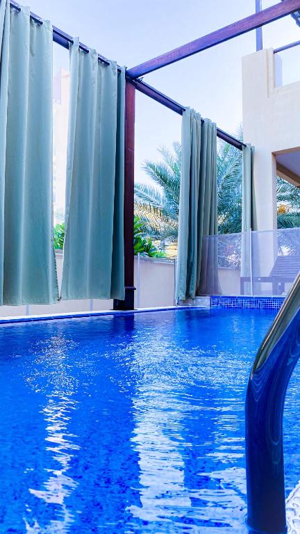 una gran piscina con agua azul y ventanas en Mina Al Fajer Villas en Wāsiţ