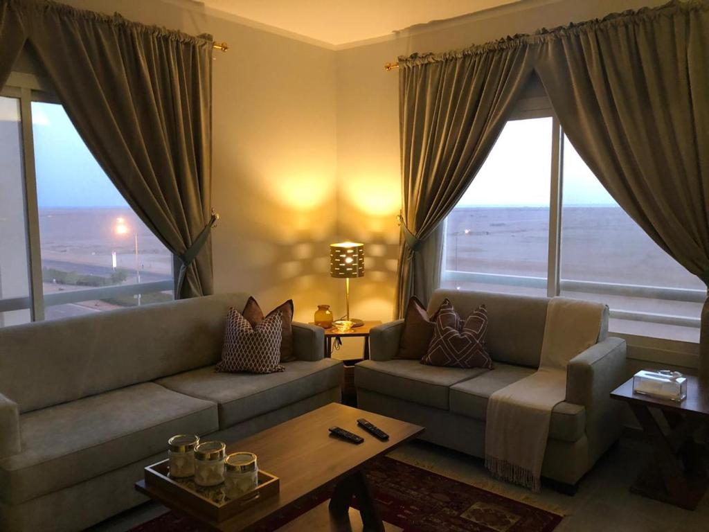 ein Wohnzimmer mit einem Sofa, einem Tisch und Fenstern in der Unterkunft الشروق شقه فندقيه vip البيت بيتك in King Abdullah Economic City