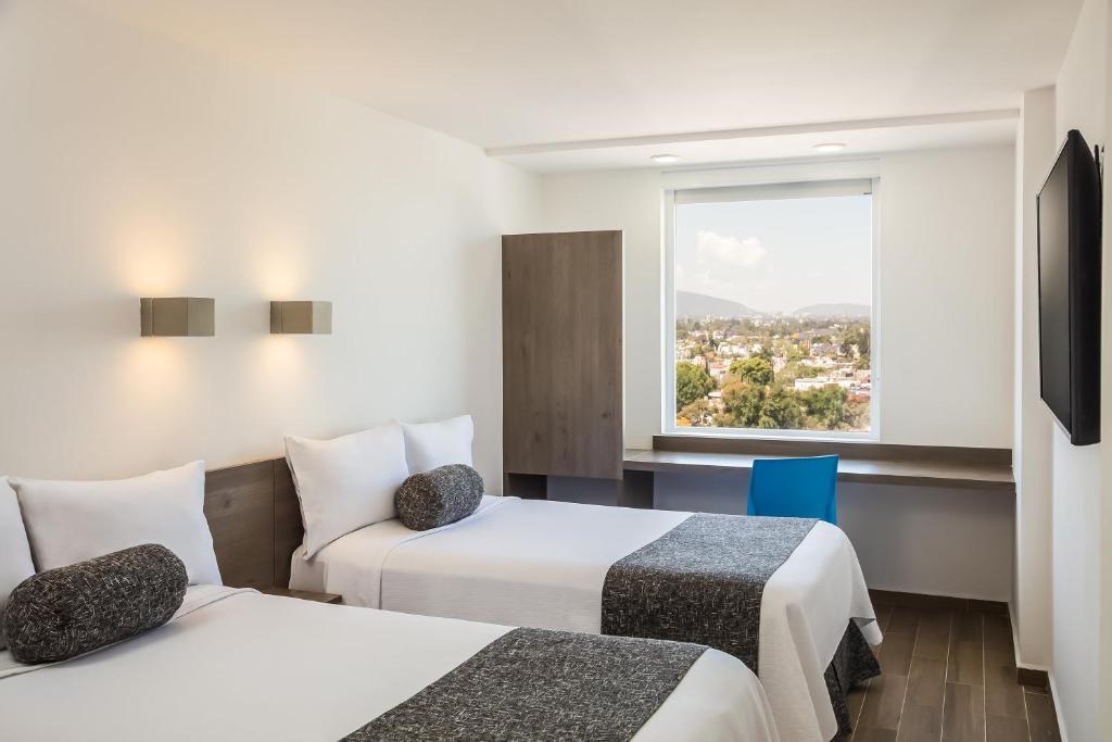 een hotelkamer met 2 bedden en een raam bij One Ciudad de Mexico La Raza in Mexico-Stad