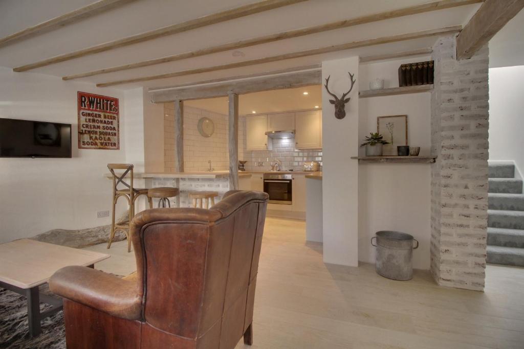 uma sala de estar com uma cadeira e uma cozinha em Willow Cottage em Westerham