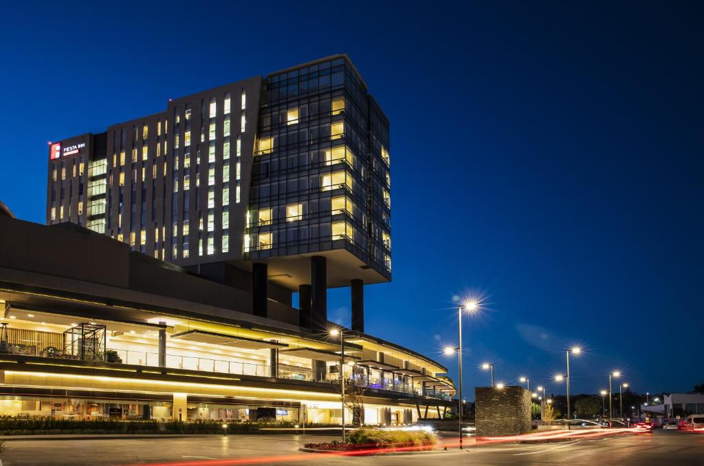 un edificio alto con muchas ventanas por la noche en Fiesta Inn Express Queretaro Constituyentes en Querétaro